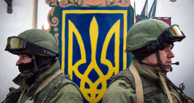 Armed men in military uniform stand near the Ukrainian coat of arms, outside the territory of a Ukrainian military unit in the village of Perevalnoye, outside Simferopol today. Photograph: Alexey Furman/EPA